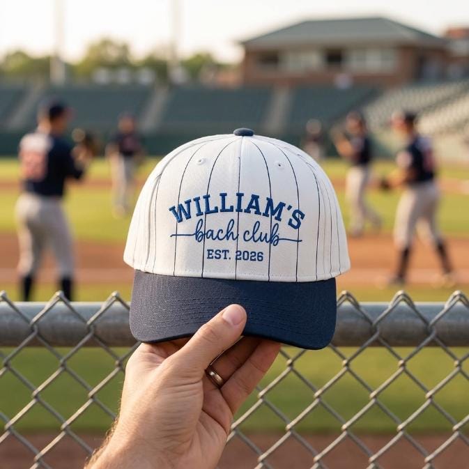 Front view of William’s Beach Club embroidered pinstripe hat held near a baseball field