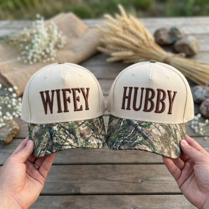 Matching Wifey and Hubby trucker hats with cream crowns and camouflage-patterned bills