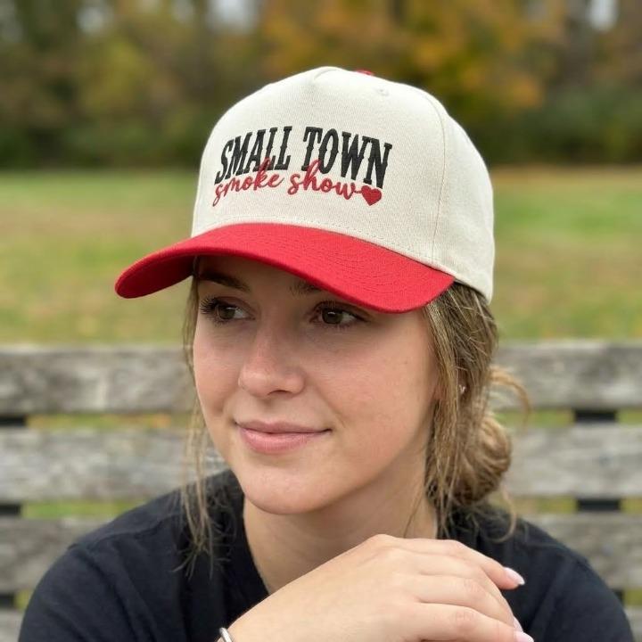 Person wearing the cream and red Small Town Smoke Show embroidered hat