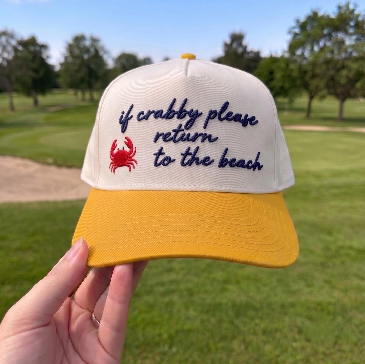 Funny baseball cap with a yellow brim, white top featuring a red crab and the embroidered phrase 'if crabby please return to