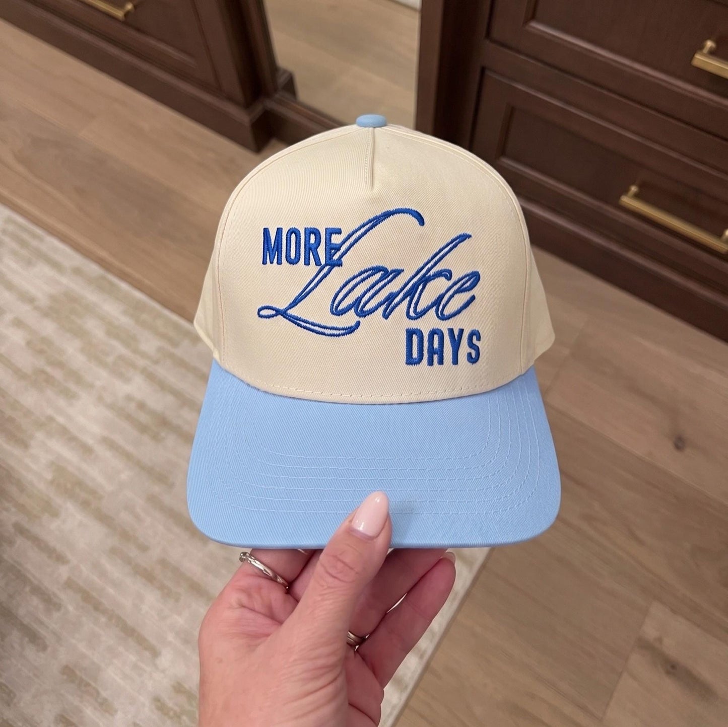 Embroidered cap with 'More Lake Days' in blue on beige and light blue background