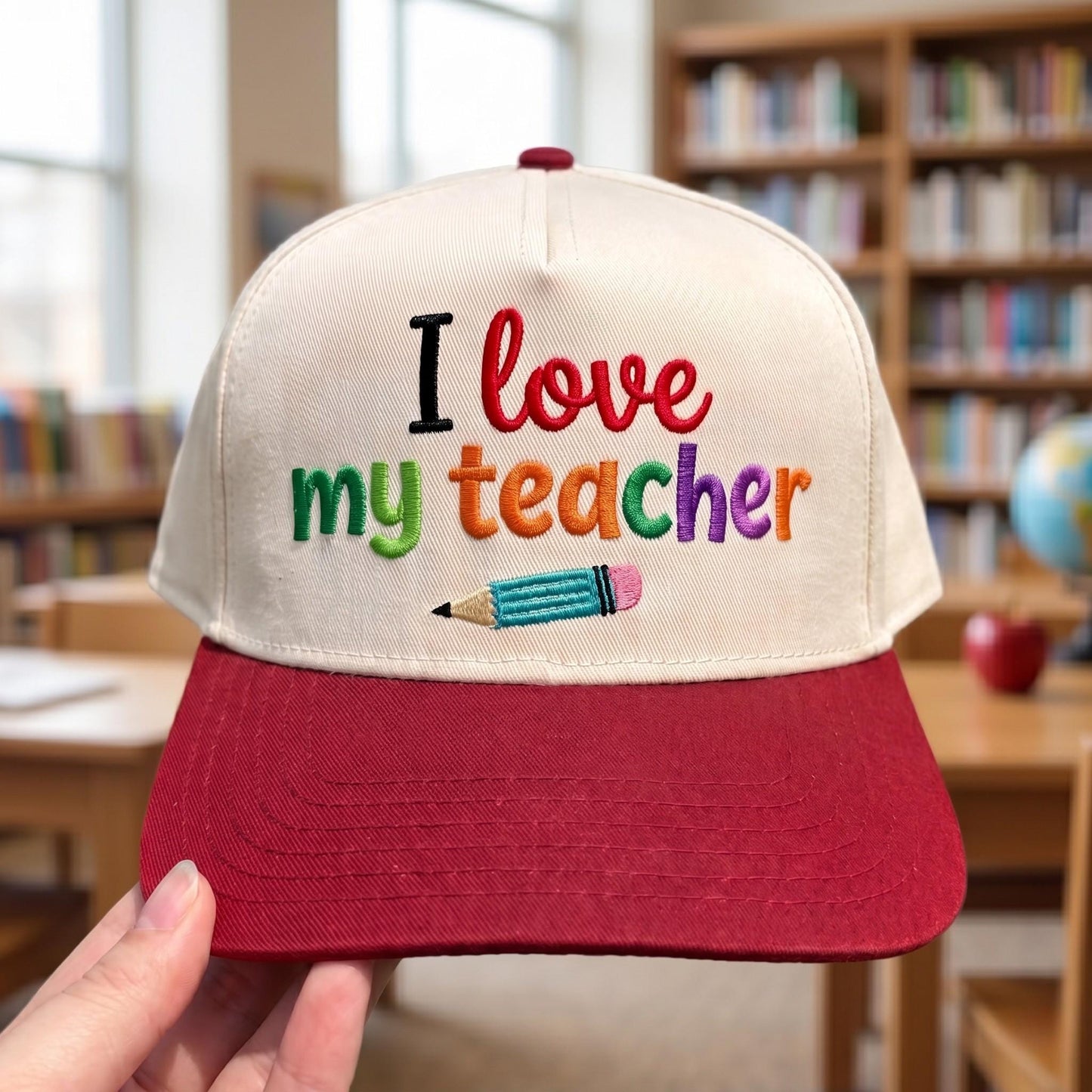 Embroidered cap with 'I love my teacher' text in colorful embroidery and pencil motif, cream with red brim