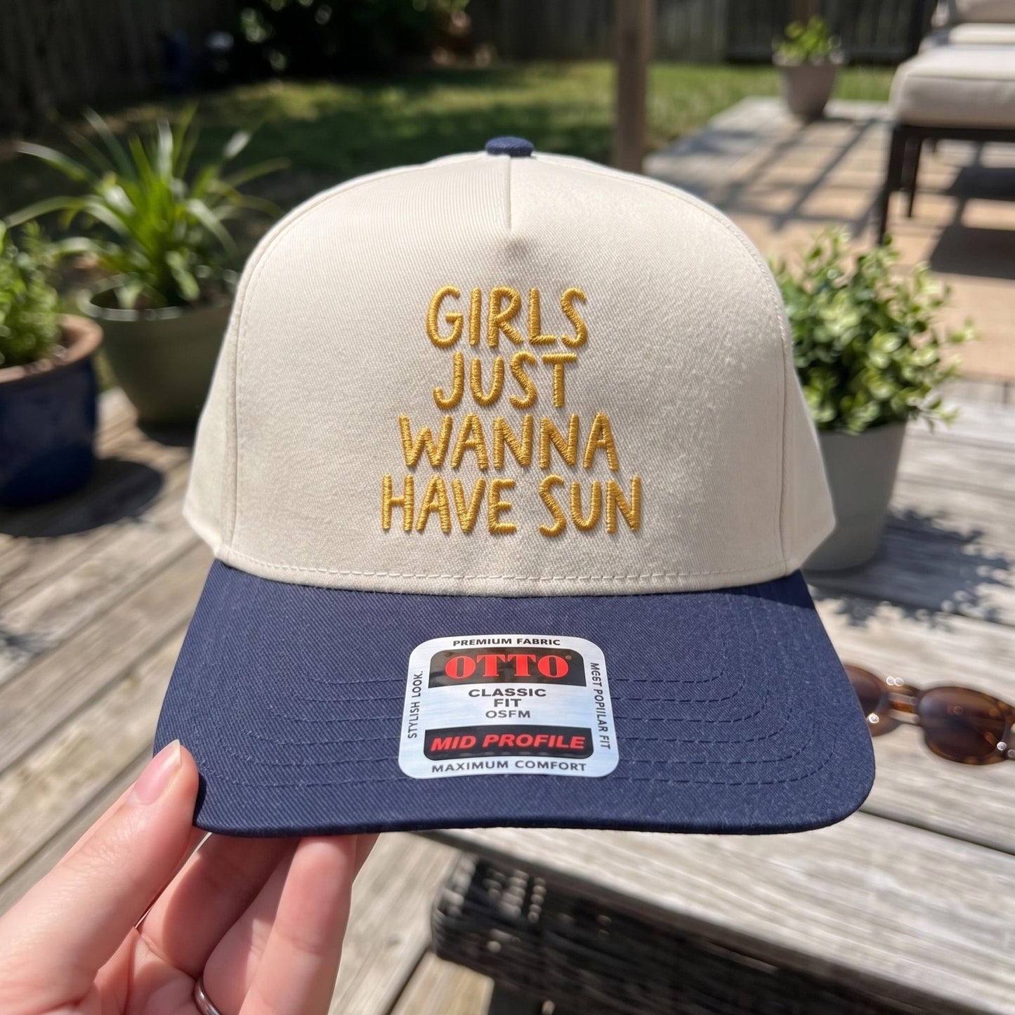Trendy sun catching cap with fun embroidery, cream and navy color, displayed outdoors
