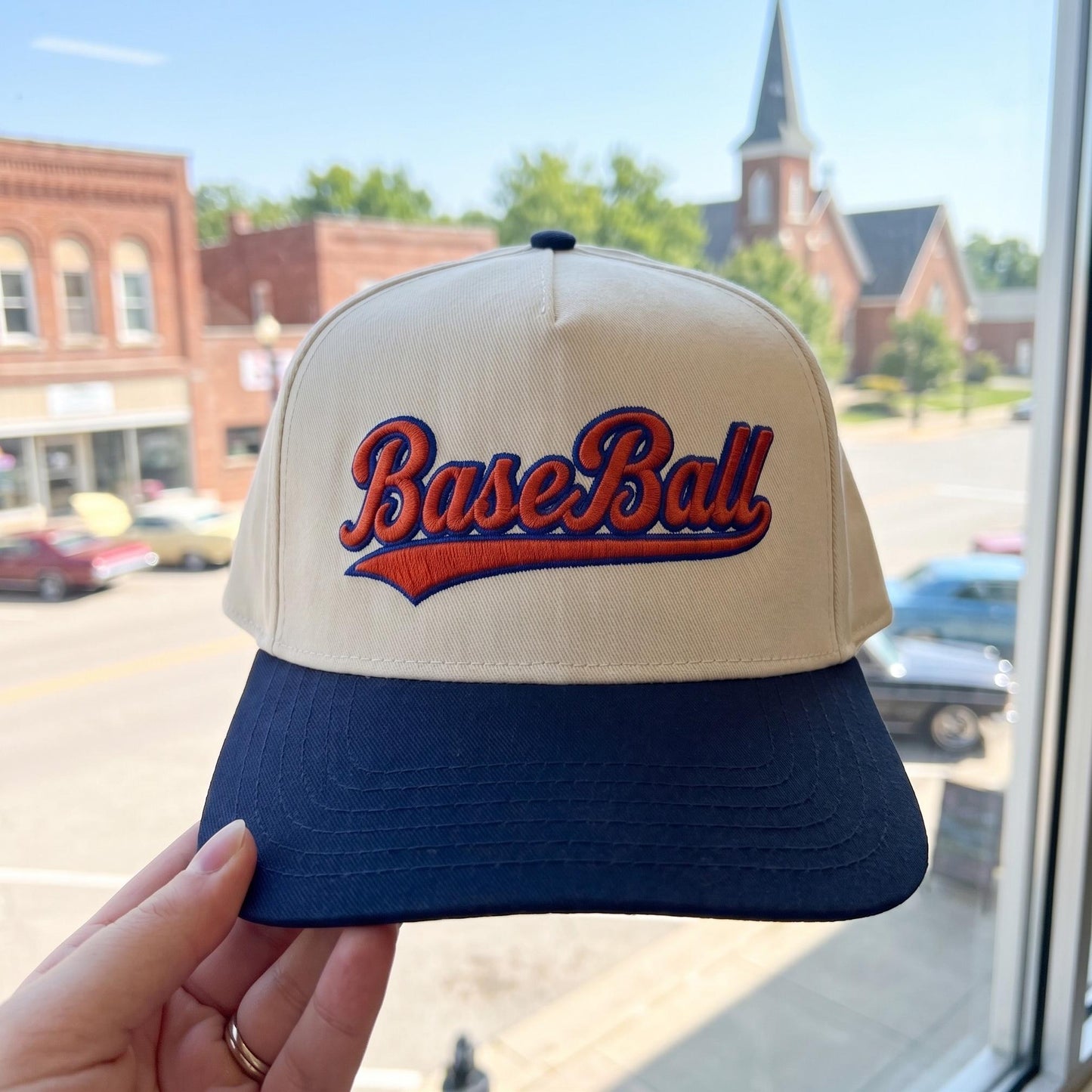 Vintage style baseball cap with embroidered 'Baseball' lettering in cream and navy on a street background
