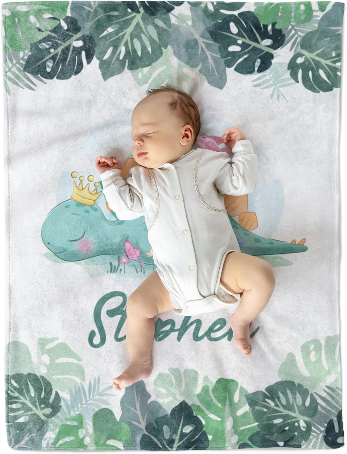 Baby lying on personalized dinosaur baby blanket with green foliage