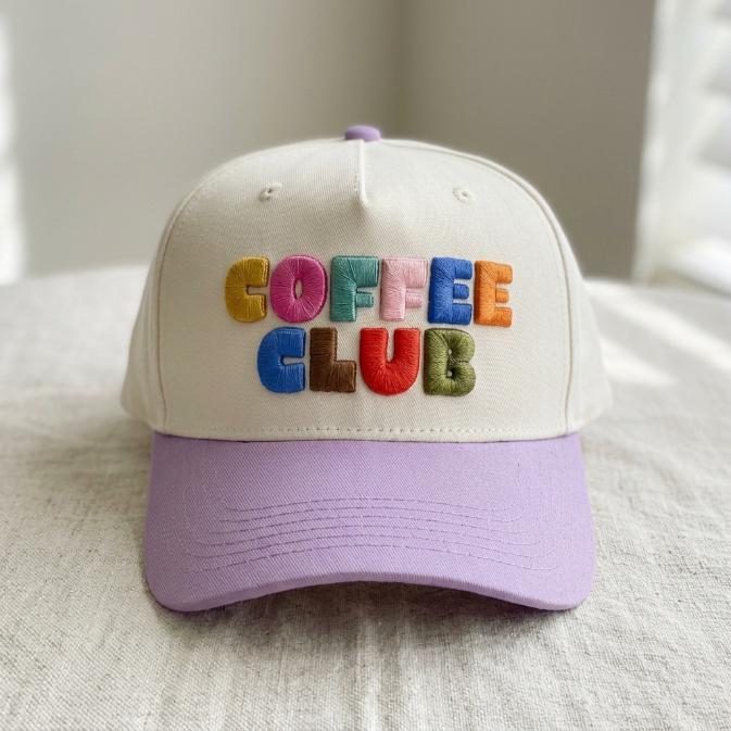 Front view of cream and lavender embroidered Coffee Club cap with colorful raised lettering