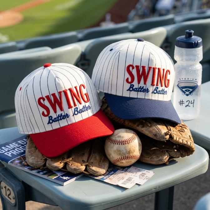 Swing Batter Batter pinstripe hats resting on baseball gloves beside a baseball in stadium seating