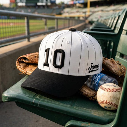 White and black number 10 pinstripe baseball hat resting on a stadium seat with baseball glove and ball