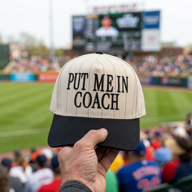 Put Me In Coach pinstripe baseball hat held at a baseball stadium