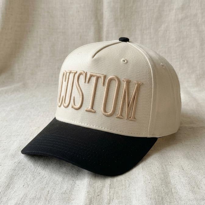 Angled view of a two-tone embroidered CUSTOM trucker hat with a black curved brim