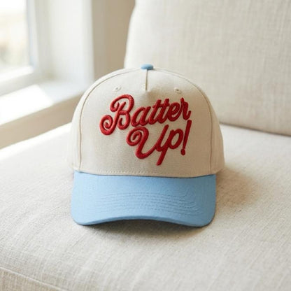 Front view of a cream and light blue Batter Up baseball trucker cap with red script embroidery