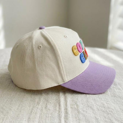 Side view showing the cream paneled crown and lavender curved brim of the cap