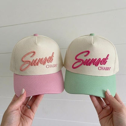 Two pastel Sunset Chasin' embroidered trucker caps in pink and mint colorways