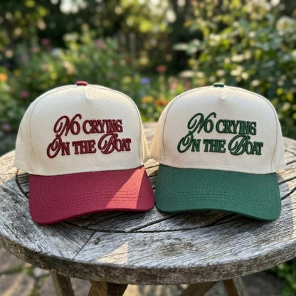 Burgundy and forest green No Crying on the Boat embroidered trucker hats displayed outdoors
