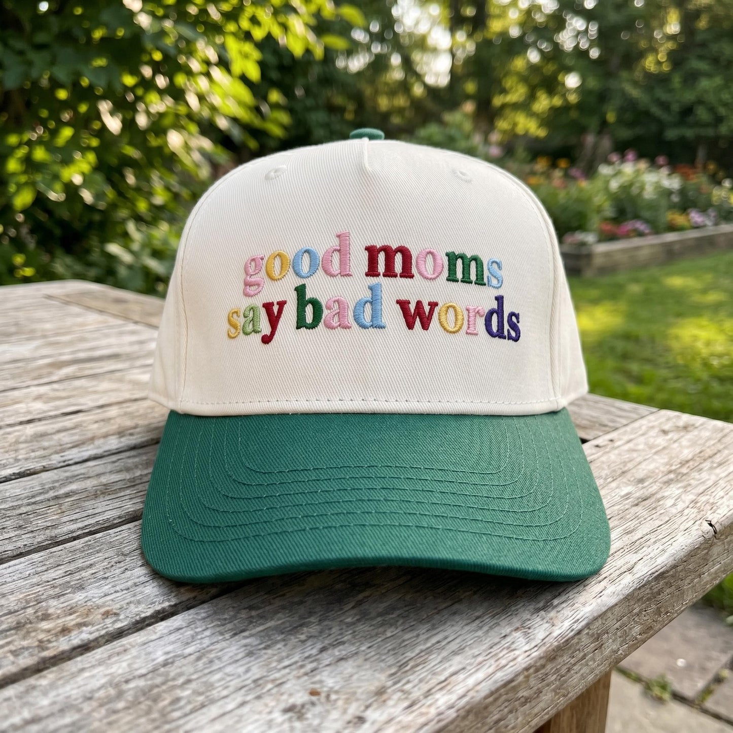 Close-up of embroidered good moms say bad words phrase on a two-tone cap