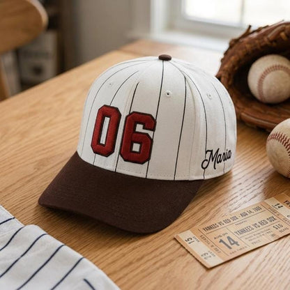 Pinstripe baseball hat with red 06 displayed on a wooden table with baseballs and a glove