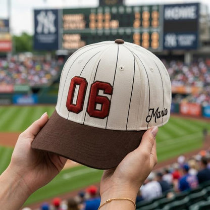 White pinstripe baseball hat with red 06 embroidery, brown brim, and Maria script detail