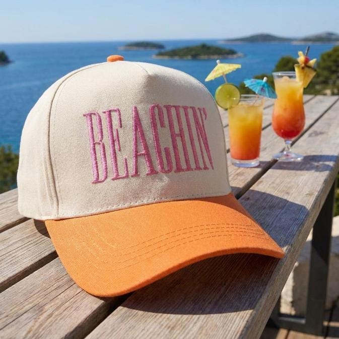 Beachin’ two-tone cap styled on a deck beside colorful tropical drinks