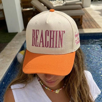 Front view of a cream and orange Beachin’ trucker cap worn by a model