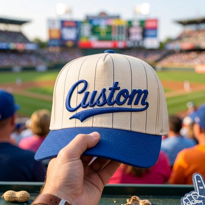 Cream pinstripe baseball hat with blue bill and raised Custom script at a baseball stadium