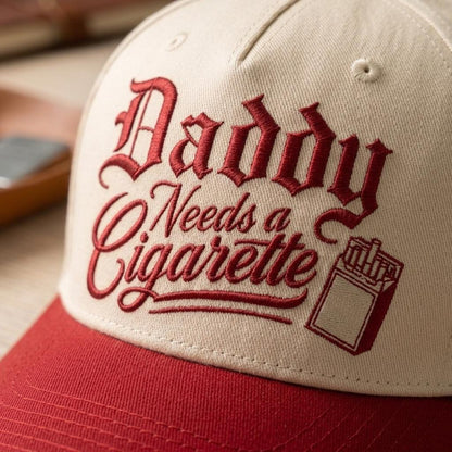 Close-up of vintage-style script embroidery and cigarette-pack graphic on cap