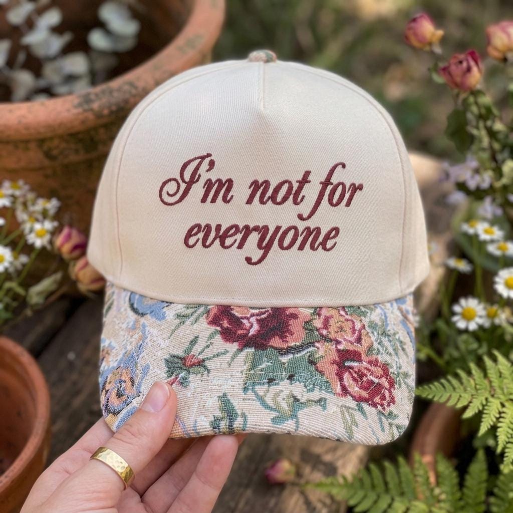 Front view of floral brim statement hat held in a garden setting