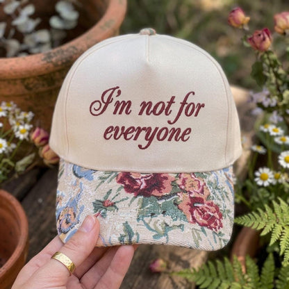 Front view of floral brim statement hat held in a garden setting
