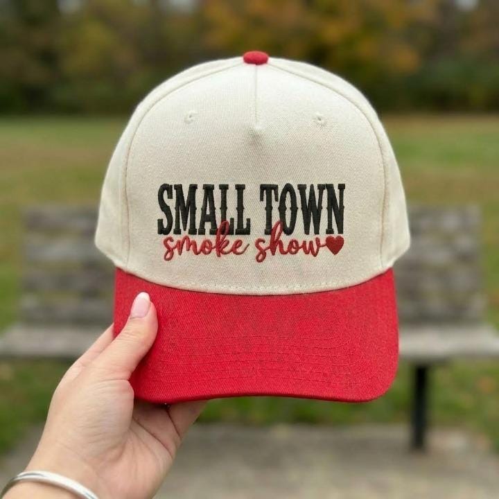 Front view of a cream and red embroidered Small Town Smoke Show hat with a heart detail