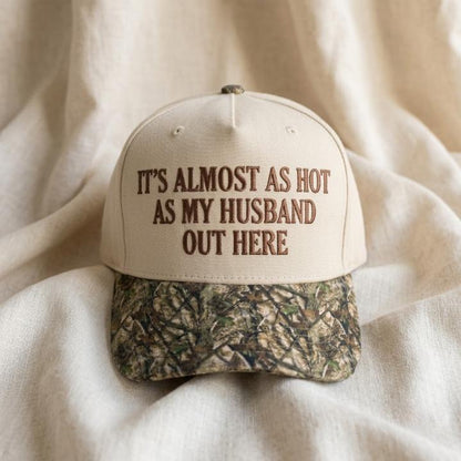 Cream funny saying hat with camouflage brim on a light wood table