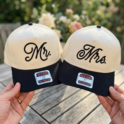 Matching cream and black Mr. and Mrs. embroidered trucker hats displayed together