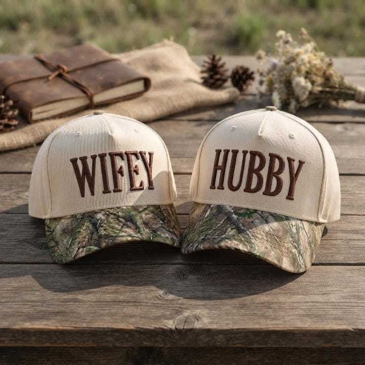 Wifey and Hubby embroidered couple hats displayed together on a wooden table