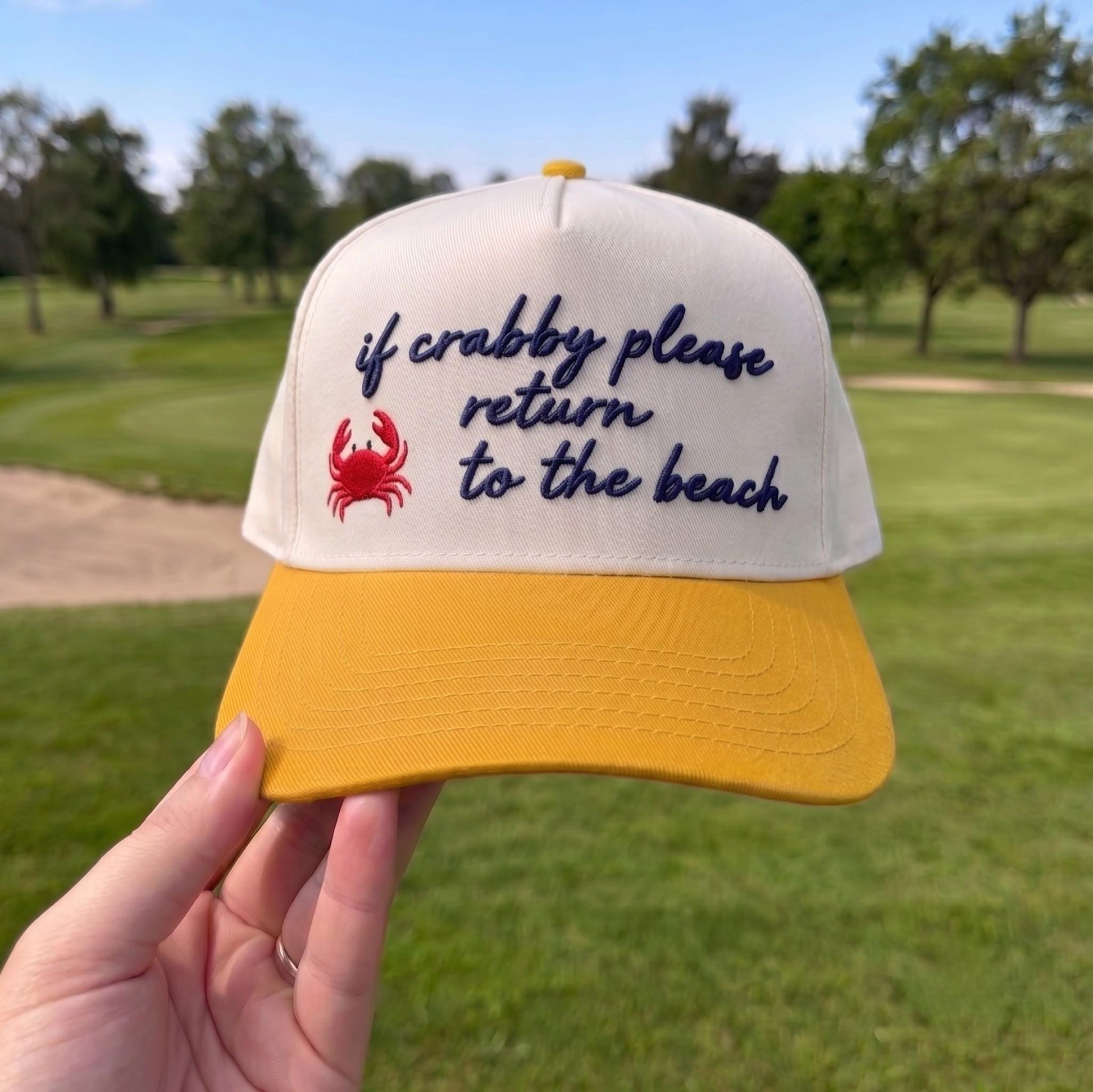 Funny baseball cap with a yellow brim, white top featuring a red crab and the embroidered phrase 'if crabby please return to