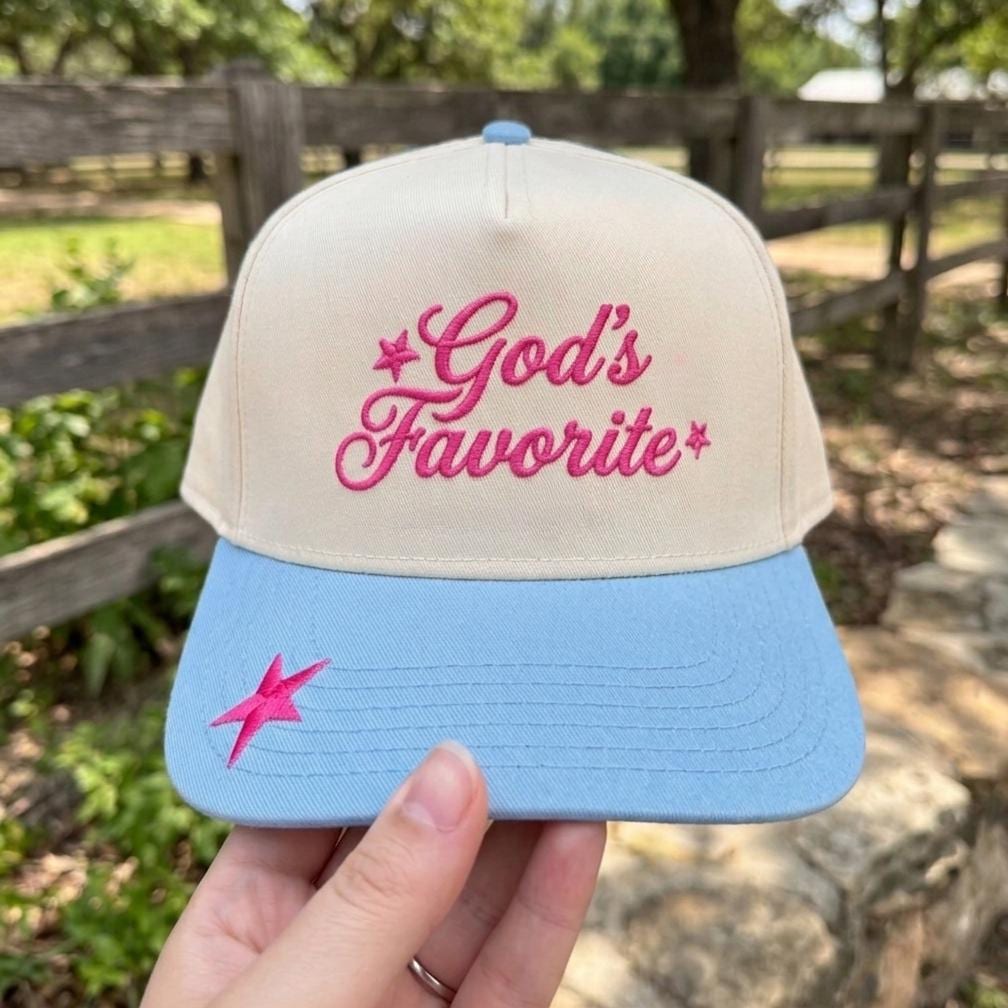 Trendy trucker cap with 'God's Favorite' embroidered in pink on beige crown with blue brim