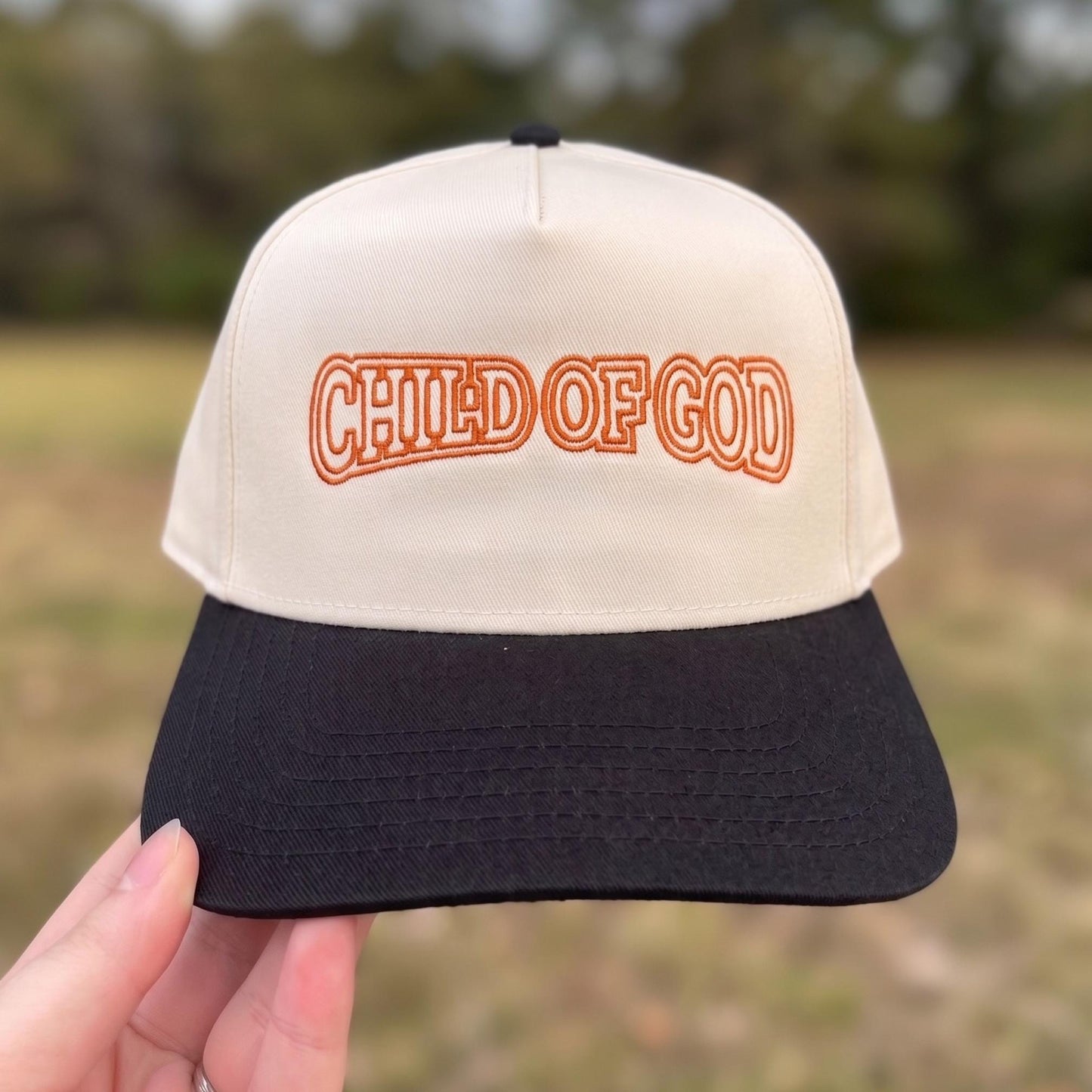 Vintage-style beige and black trucker hat with 'Child of God' embroidered in orange