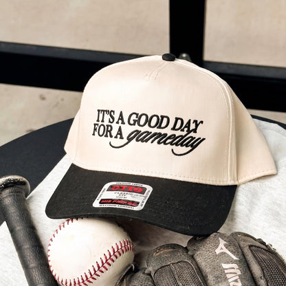 Baseball cap with 'It's A Good Day for a Gameday' embroidered in black, featuring a cream body and black brim, positioned