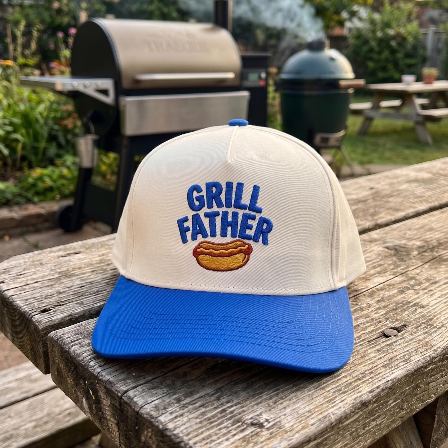 Grill Father' embroidered white and blue cap with hotdog graphic on wooden table