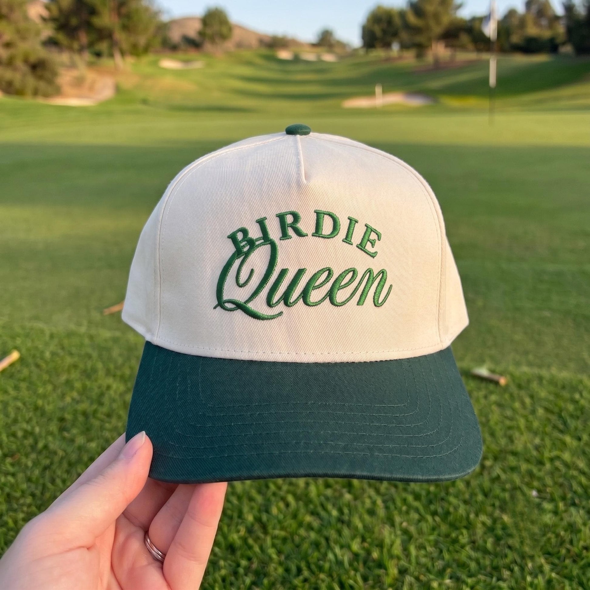 Birdie Queen' embroidered golf cap with cream crown and green bill on a golf course backdrop
