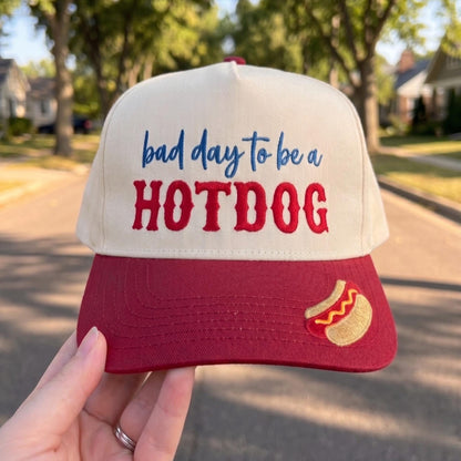 Funny baseball cap with 'Bad Day to be a Hotdog' design in cream and red colors