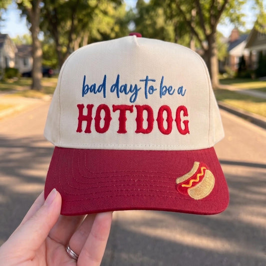 Funny baseball cap with 'Bad Day to be a Hotdog' design in cream and red colors