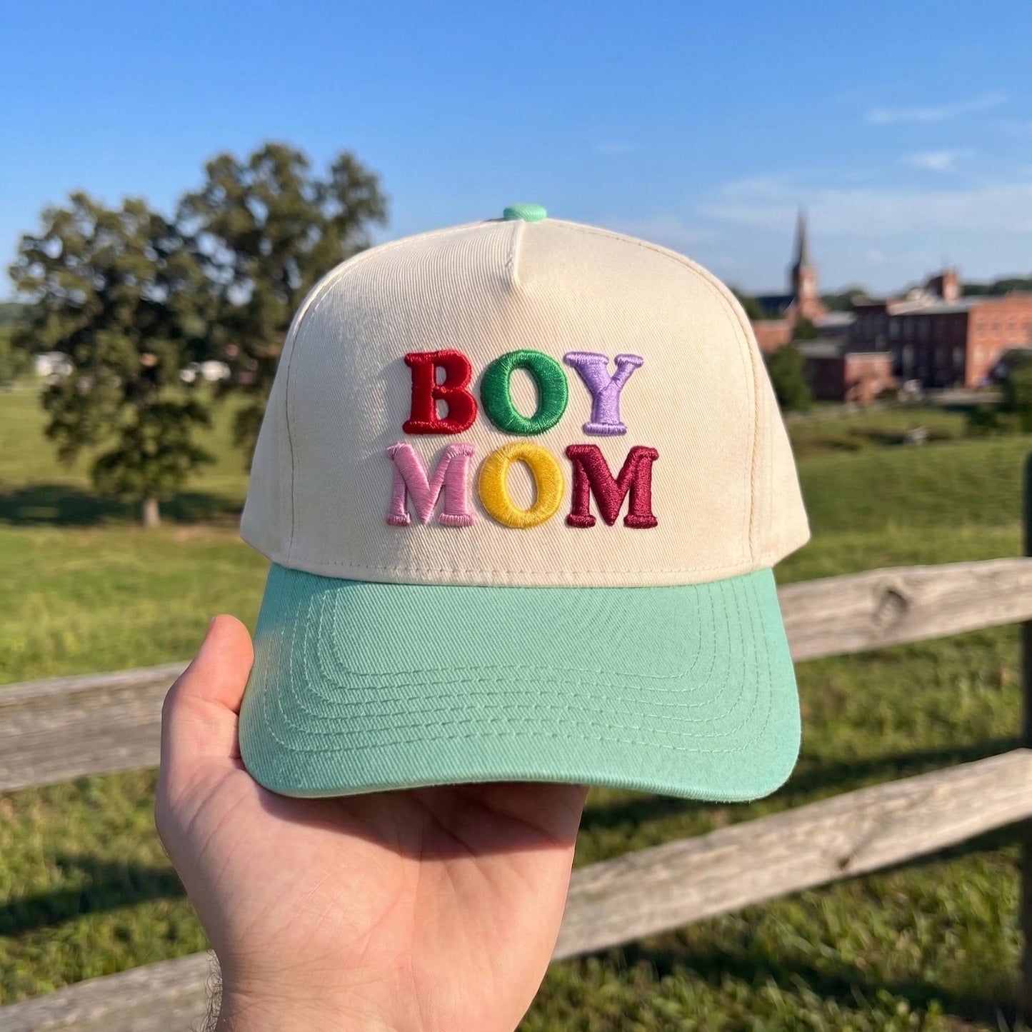Boy Mom' embroidered baseball cap with colorful letters, cream crown and mint green brim, outdoor setting