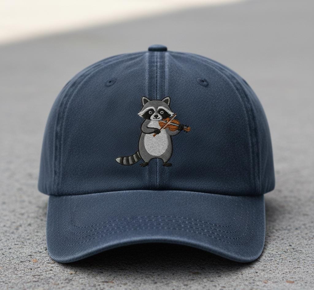 Blue baseball cap with an embroidered raccoon playing a violin displayed outdoors
