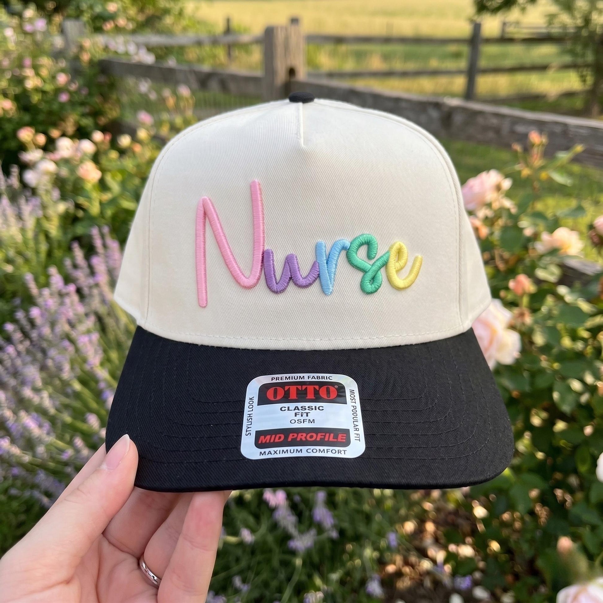 Embroidered cap with 'Nurse' in colorful letters on cream fabric with a black brim