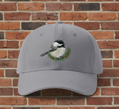 Gray cotton baseball cap with embroidered bird design and green foliage on brick background