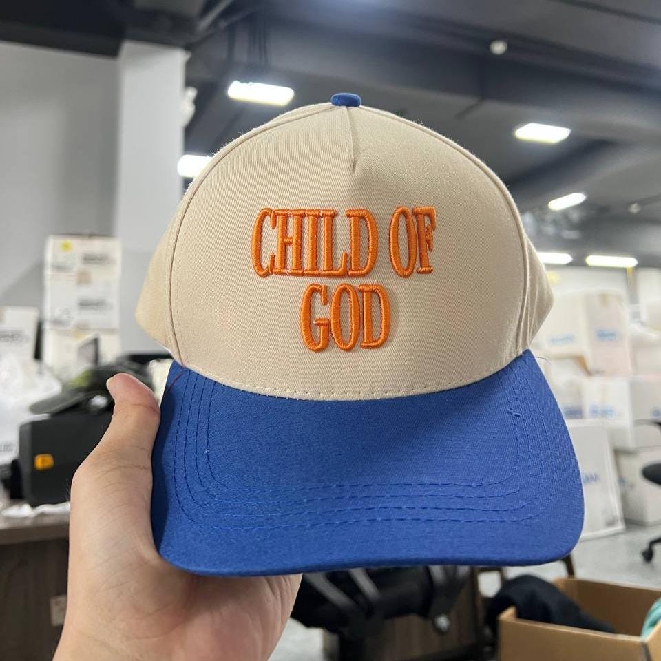 Embroidered cotton cap with 'Child of God' text in orange on beige and blue two-tone design