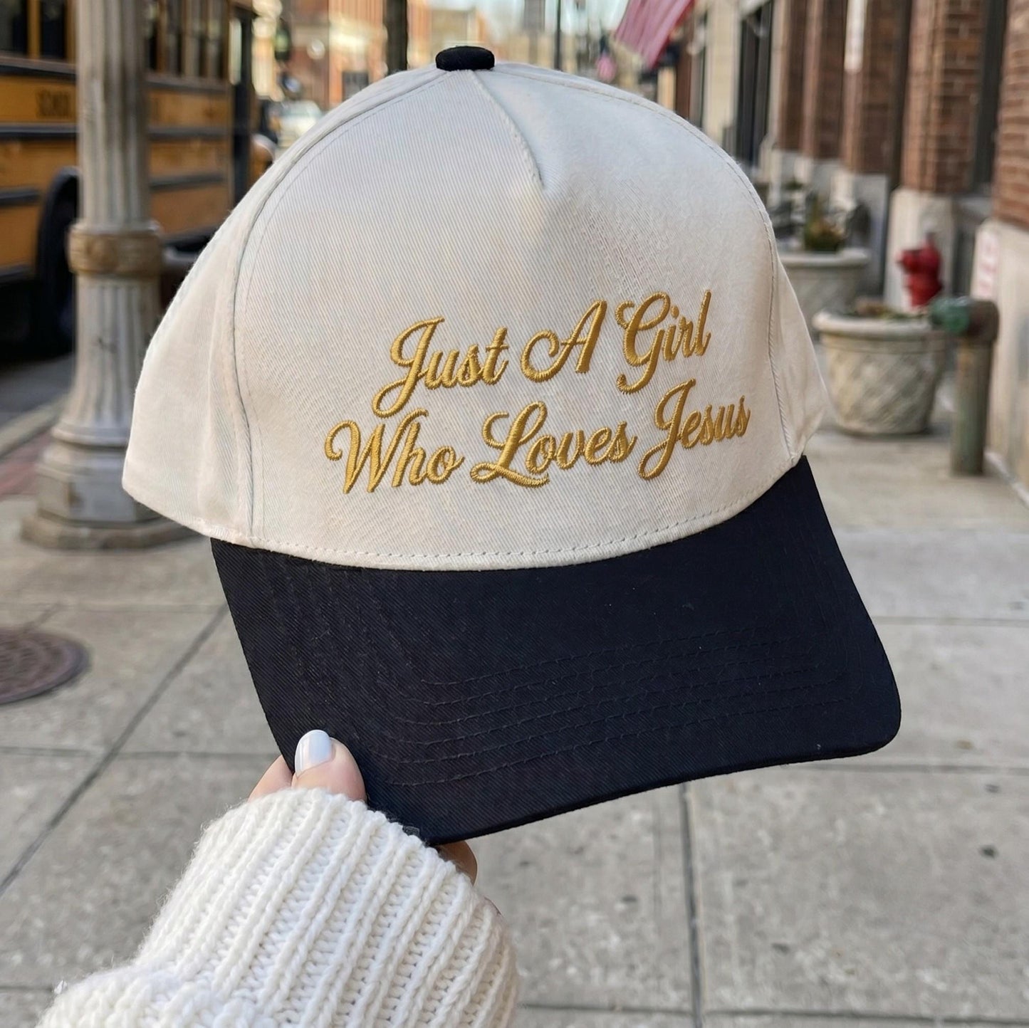 Embroidered beige and black cap with 'Just A Girl Who Loves Jesus' text in gold