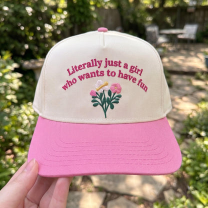 Trendy floral embroidered cap with pink brim and fun text in a garden setting