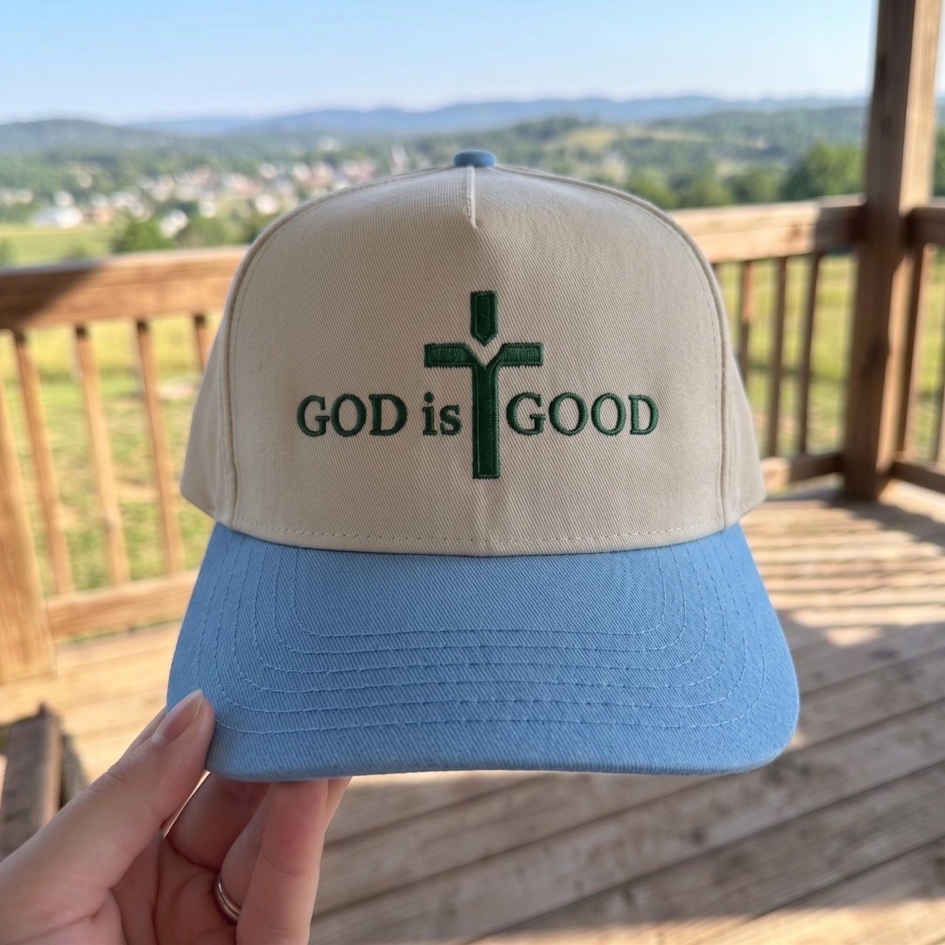 Inspirational trucker hat with 'God is Good' cross design, cream and blue color