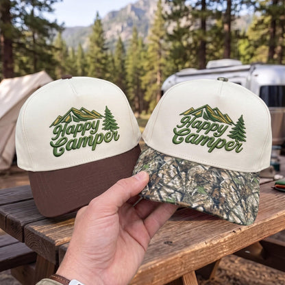 Camping hats with 'Happy Camper' embroidery, featuring brown and camouflage brim styles against a forest backdrop