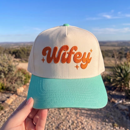 Trendy Wifey cap with cream crown and teal brim against an outdoor backdrop