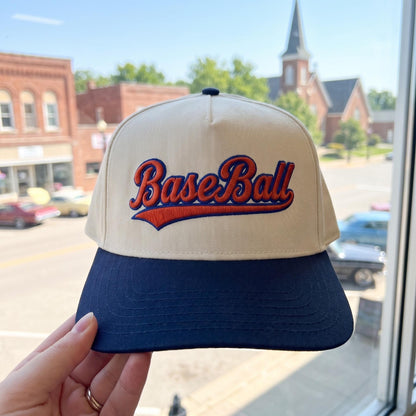 Vintage style baseball cap with embroidered 'Baseball' lettering in cream and navy on a street background